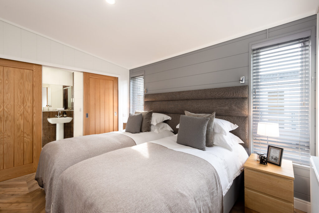 Twin beds with ensuite bathroom in neutral greys and whites